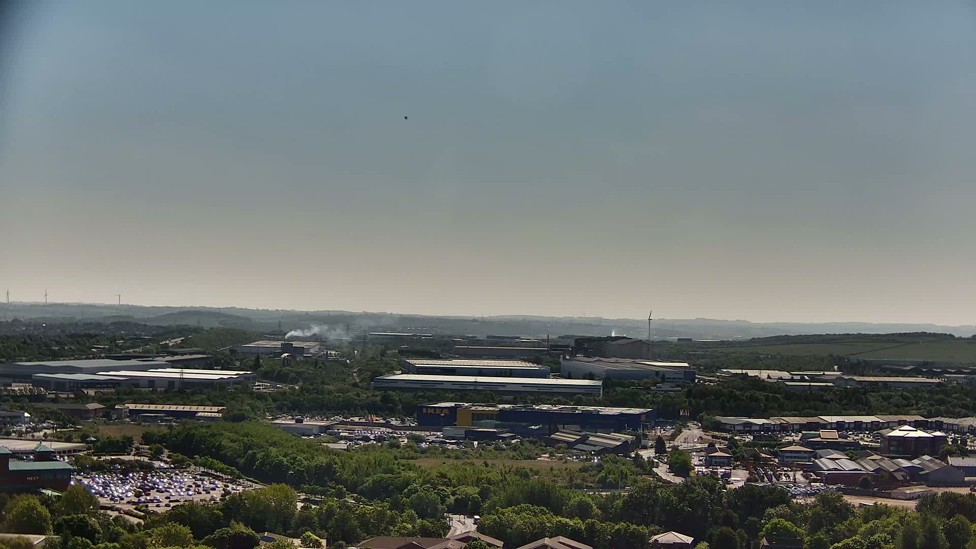 An aerial view of an industrial park and surrounding green space on a hazy day.