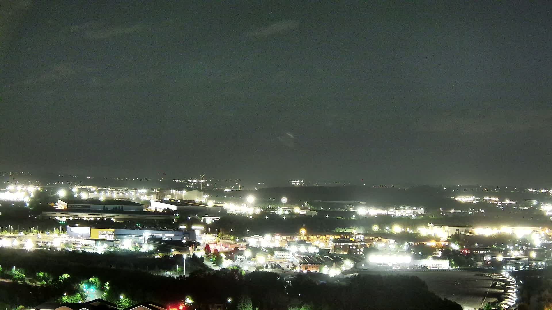 A nighttime view of an illuminated suburban area with a mostly clear sky.