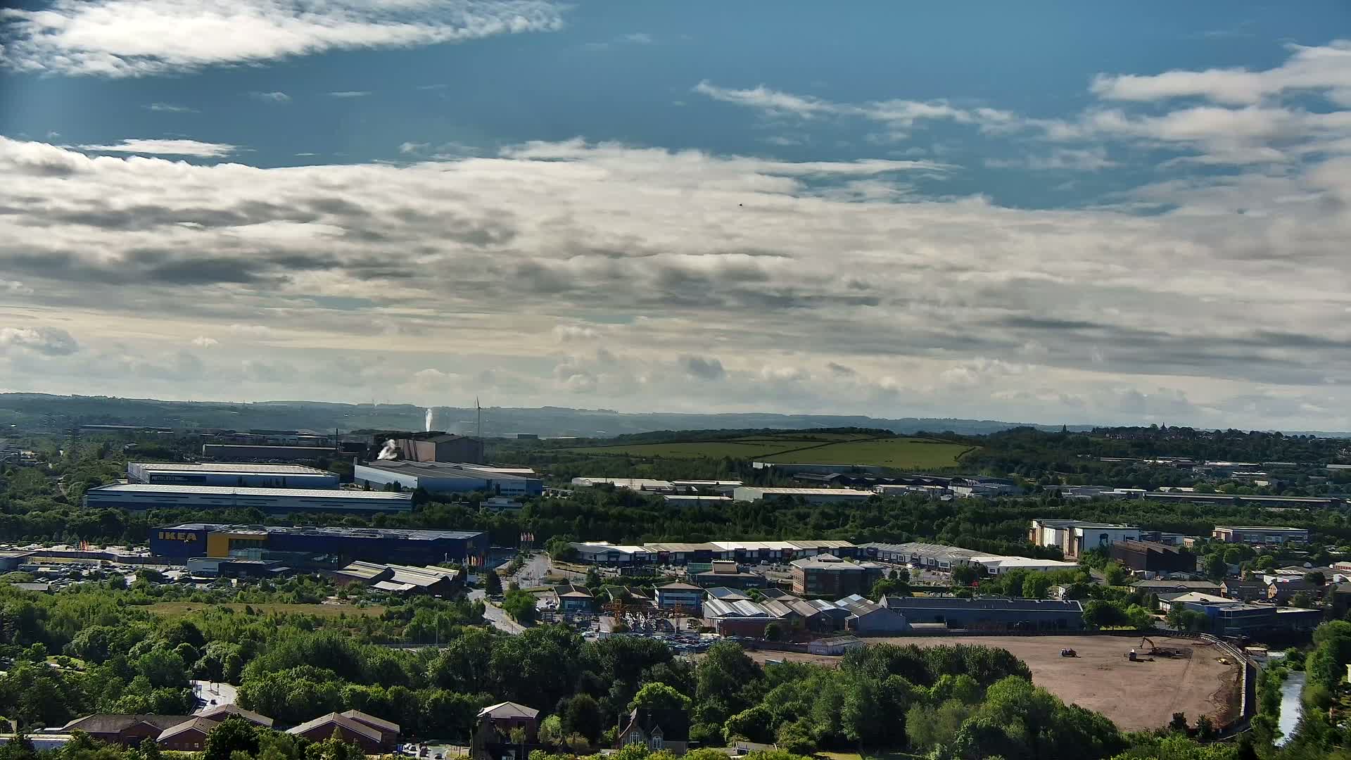 A sprawling industrial park and residential area is visible under a partly cloudy sky.