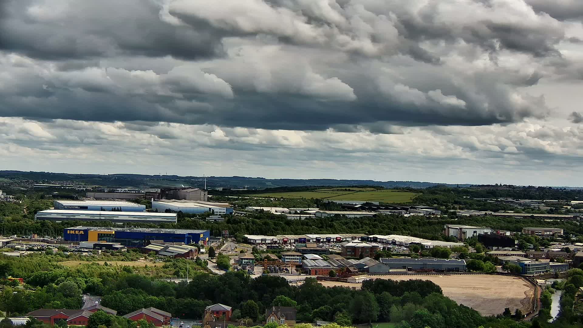 An expansive view of a sprawling industrial park and surrounding green landscape under a cloudy sky.