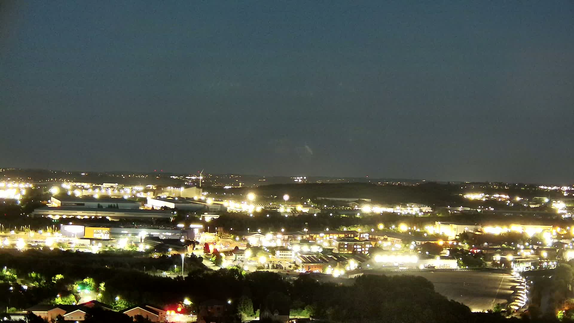 A nighttime view of an industrial and residential area, illuminated by many lights under a clear, dark sky.