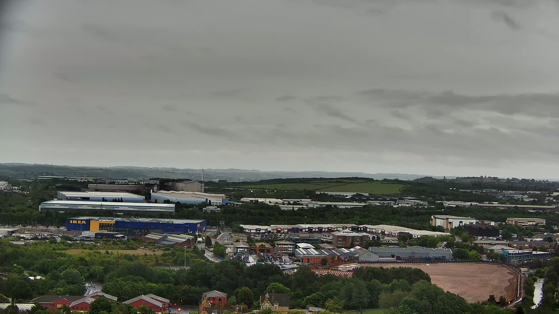 An aerial view shows an industrial and commercial area with an IKEA store under an overcast sky.
