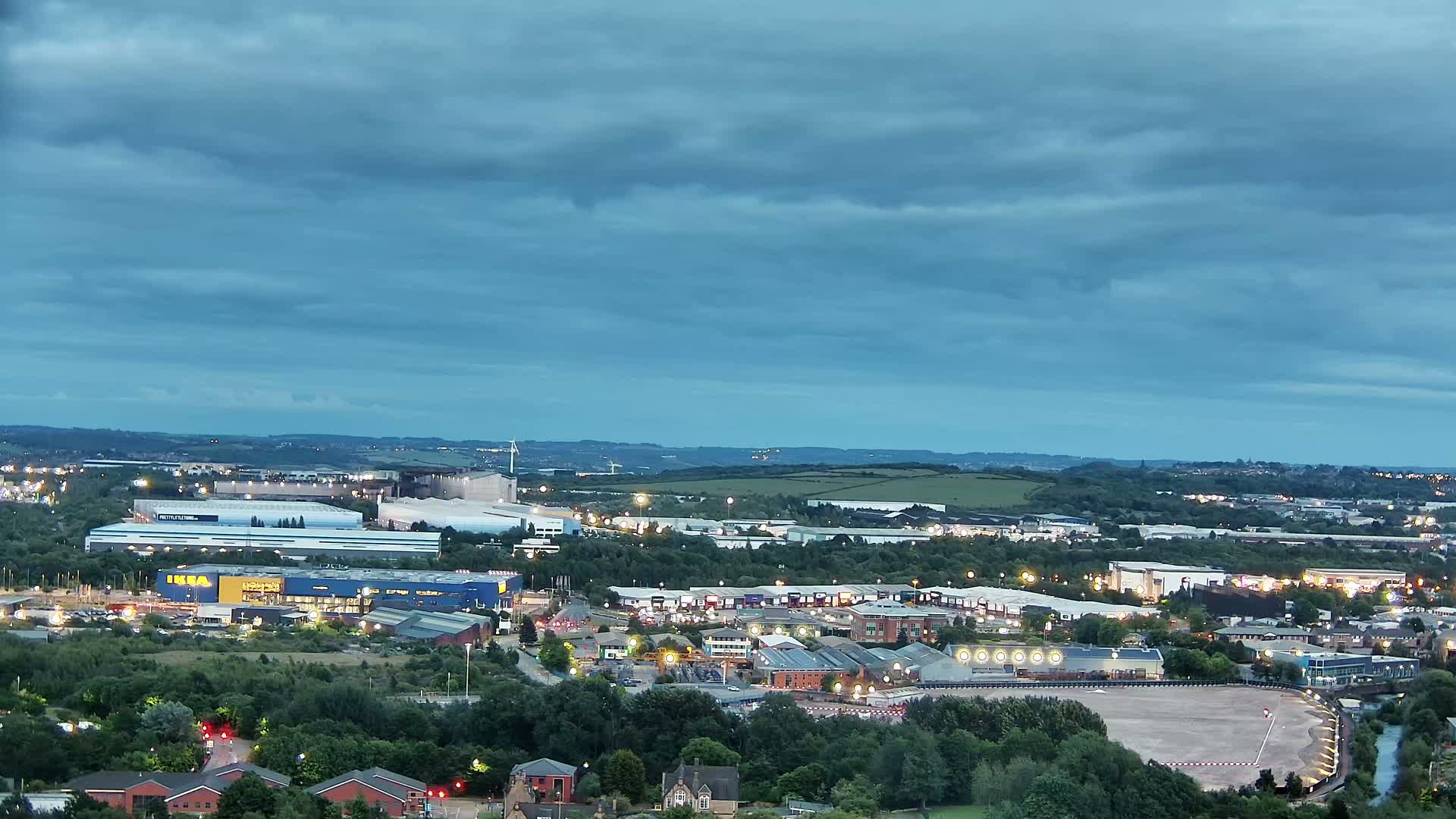 An expansive view of an industrial and residential area at dusk under a mostly cloudy sky.