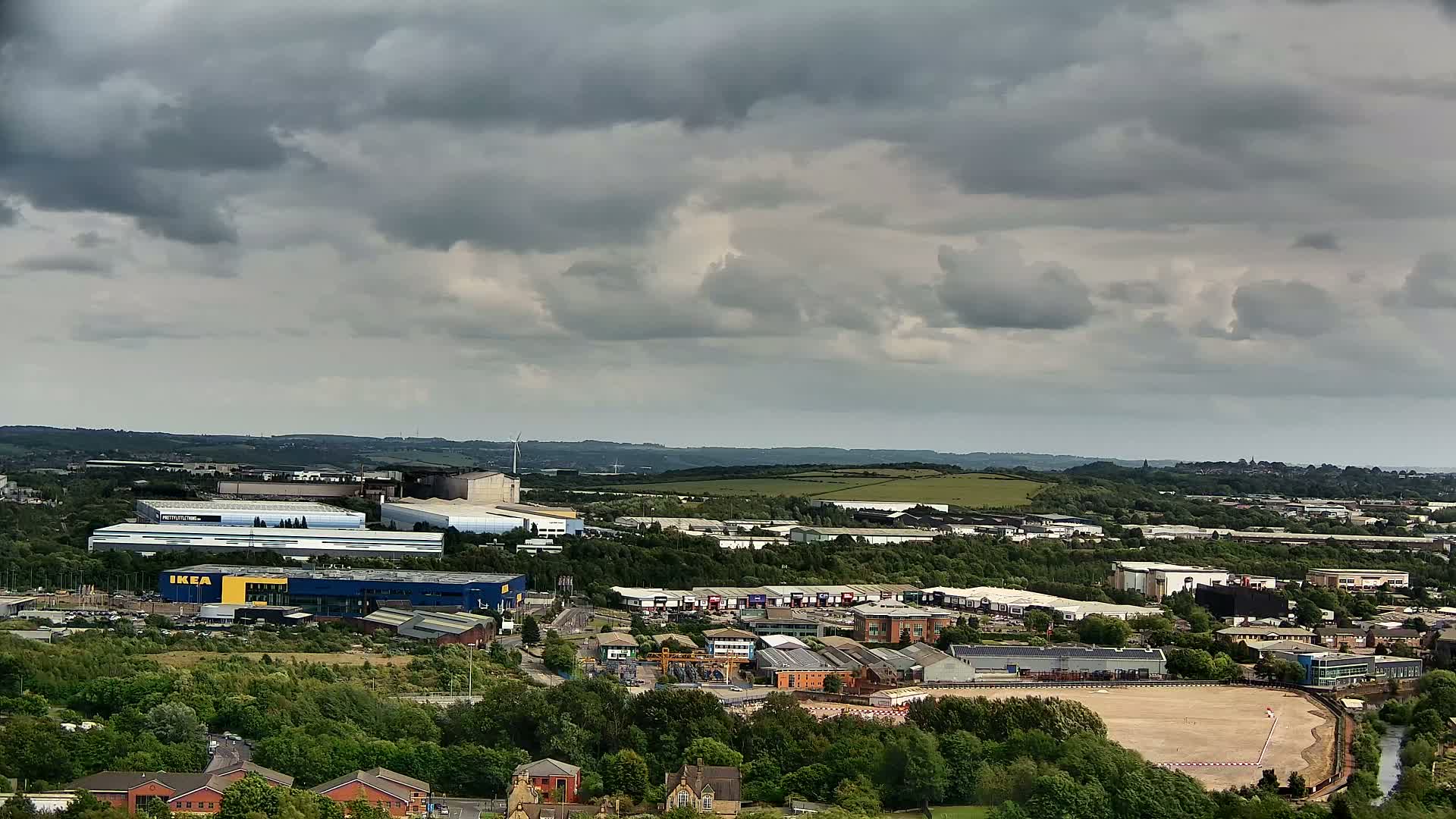 An expansive view of an industrial area, including a large blue building, under a cloudy sky.