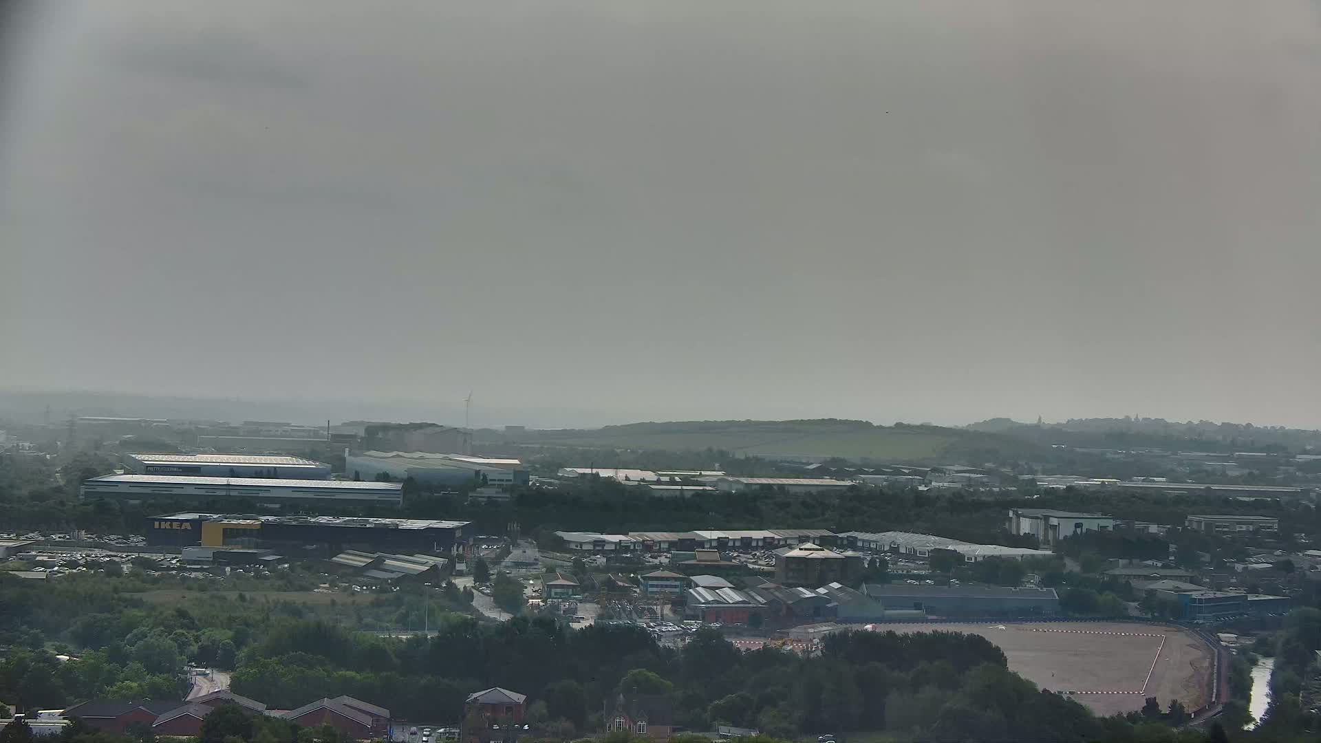 An expansive view of an industrial area and surrounding landscape under hazy, overcast skies.