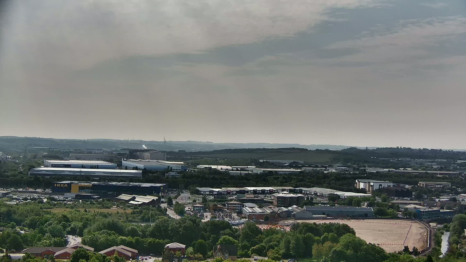 An expansive view of an industrial area and residential buildings under a hazy, overcast sky.