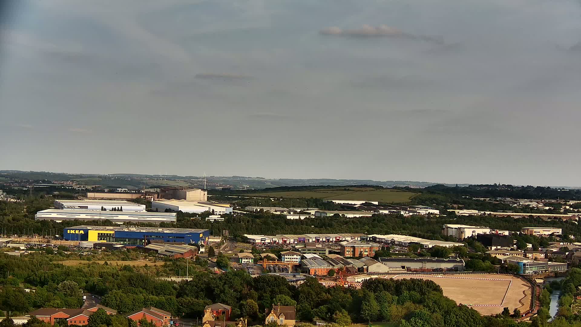 An aerial view shows an industrial and retail area, including an IKEA store, under a mostly cloudy sky.