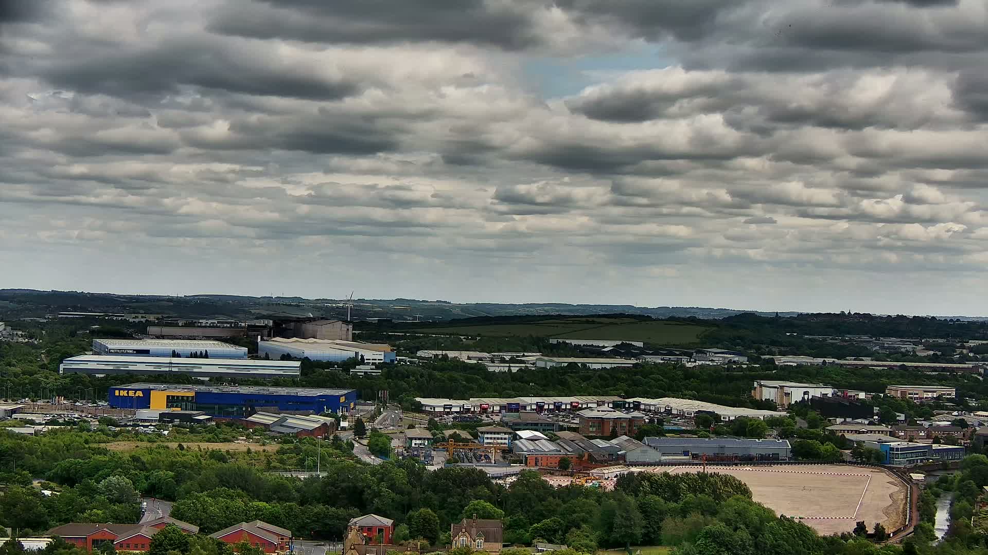 An expansive view of a landscape dotted with industrial buildings and residential areas under a cloudy sky.