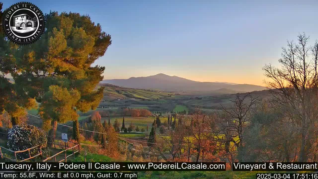 A tranquil sunset illuminates rolling hills and cypress trees in a calm,  Tuscan landscape.