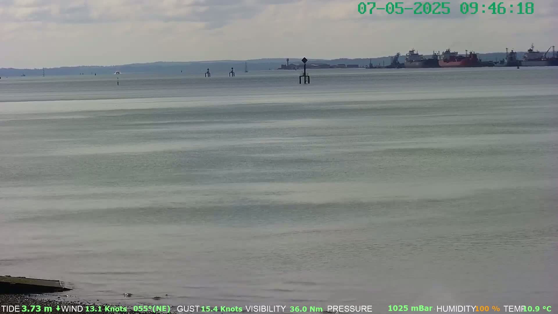 A wide shot of a calm body of water with several ships in the distance under a slightly cloudy sky.