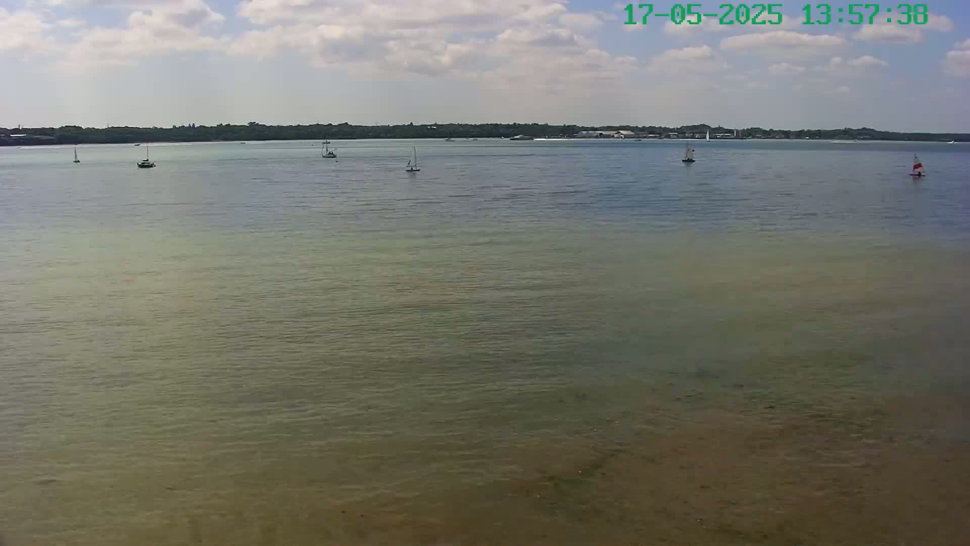 Several sailboats are visible on a calm body of water under a partly cloudy sky.