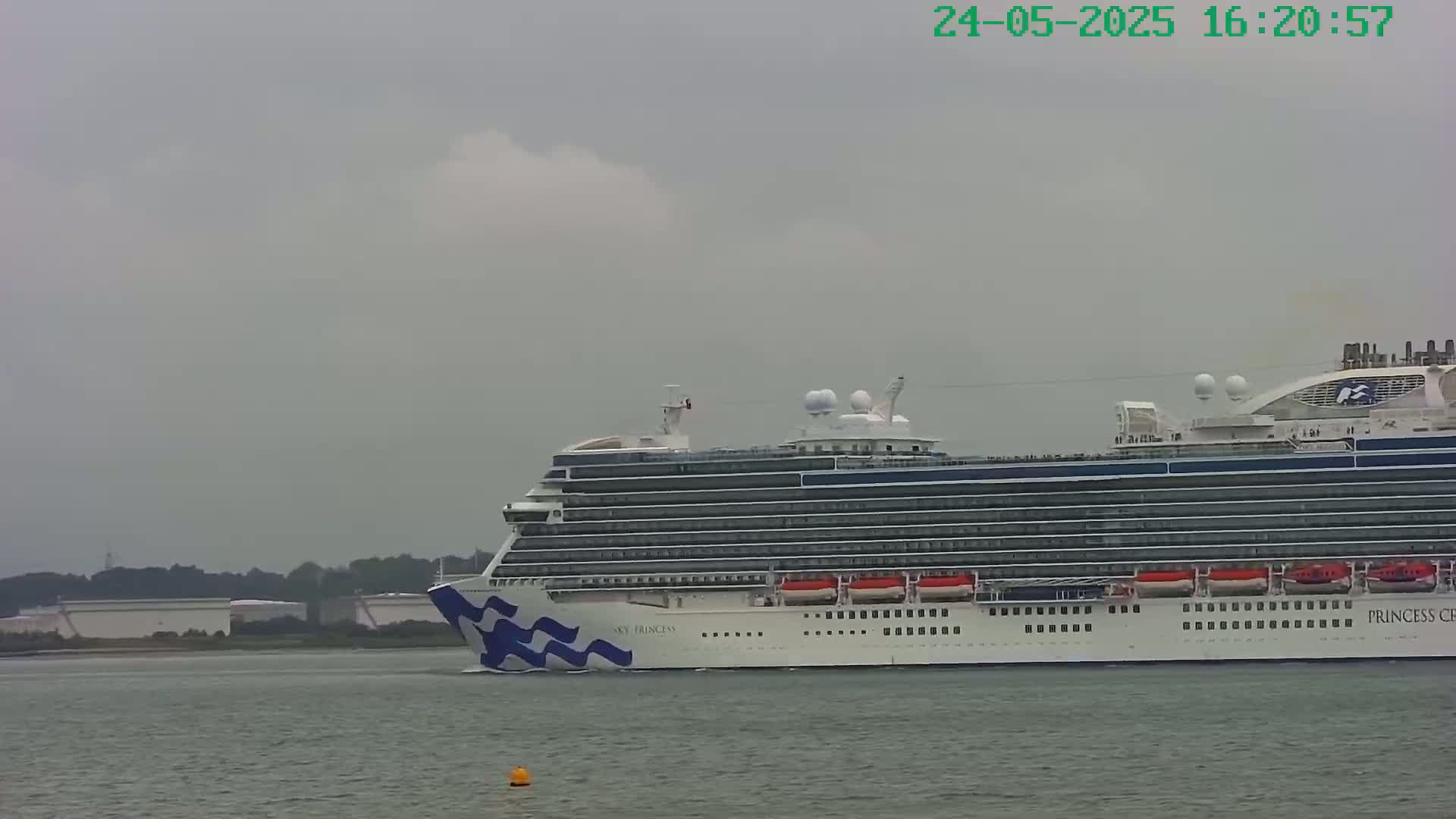 A large cruise ship sails on gray water under an overcast sky.
