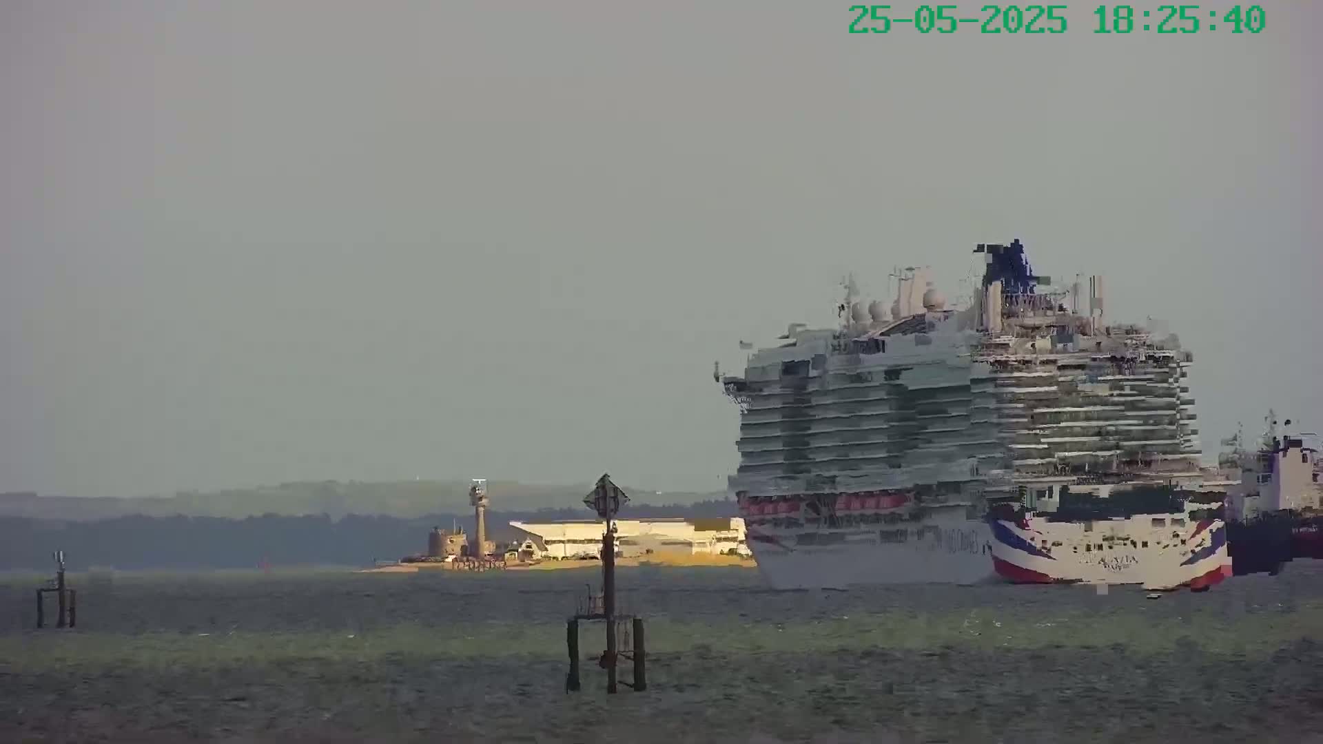 A large cruise ship is visible on hazy water near a distant shoreline with a few buildings.