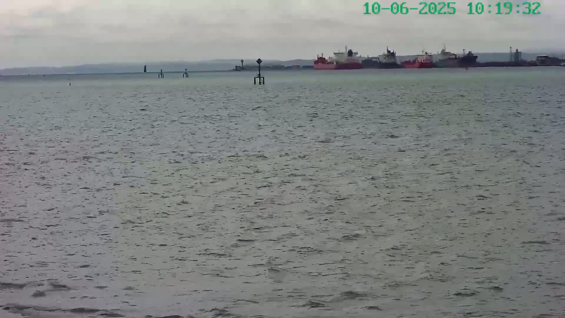 A group of ships are visible on the horizon of a choppy gray sea under an overcast sky.