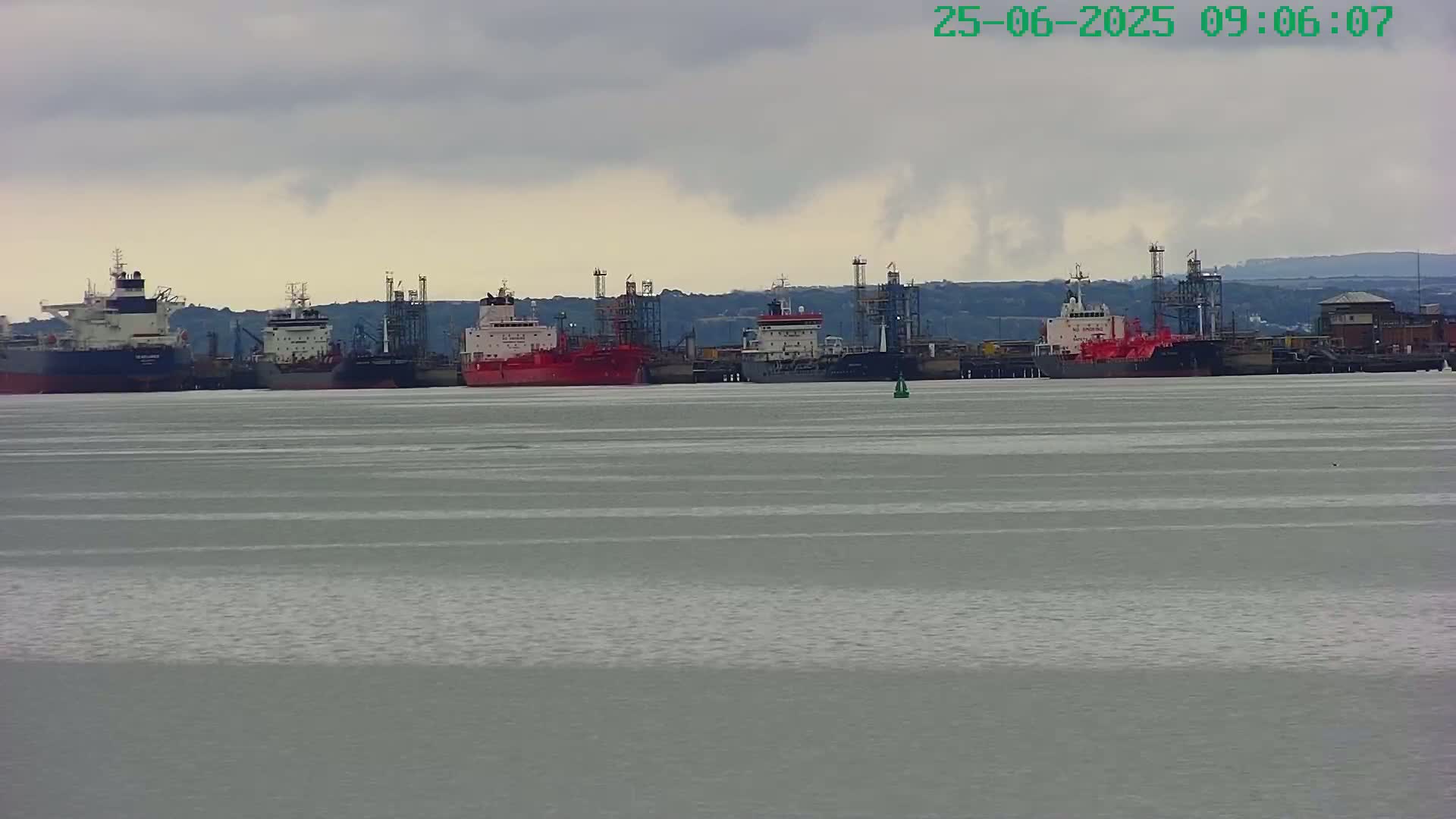Several large tankers are moored in calm, grey water under an overcast sky.