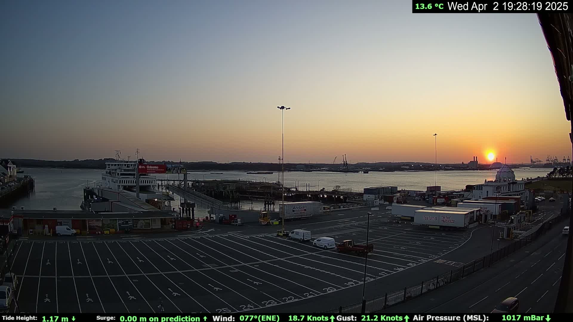 A ferry is docked at a terminal during sunset, with a mostly clear sky and calm water visible in the background.