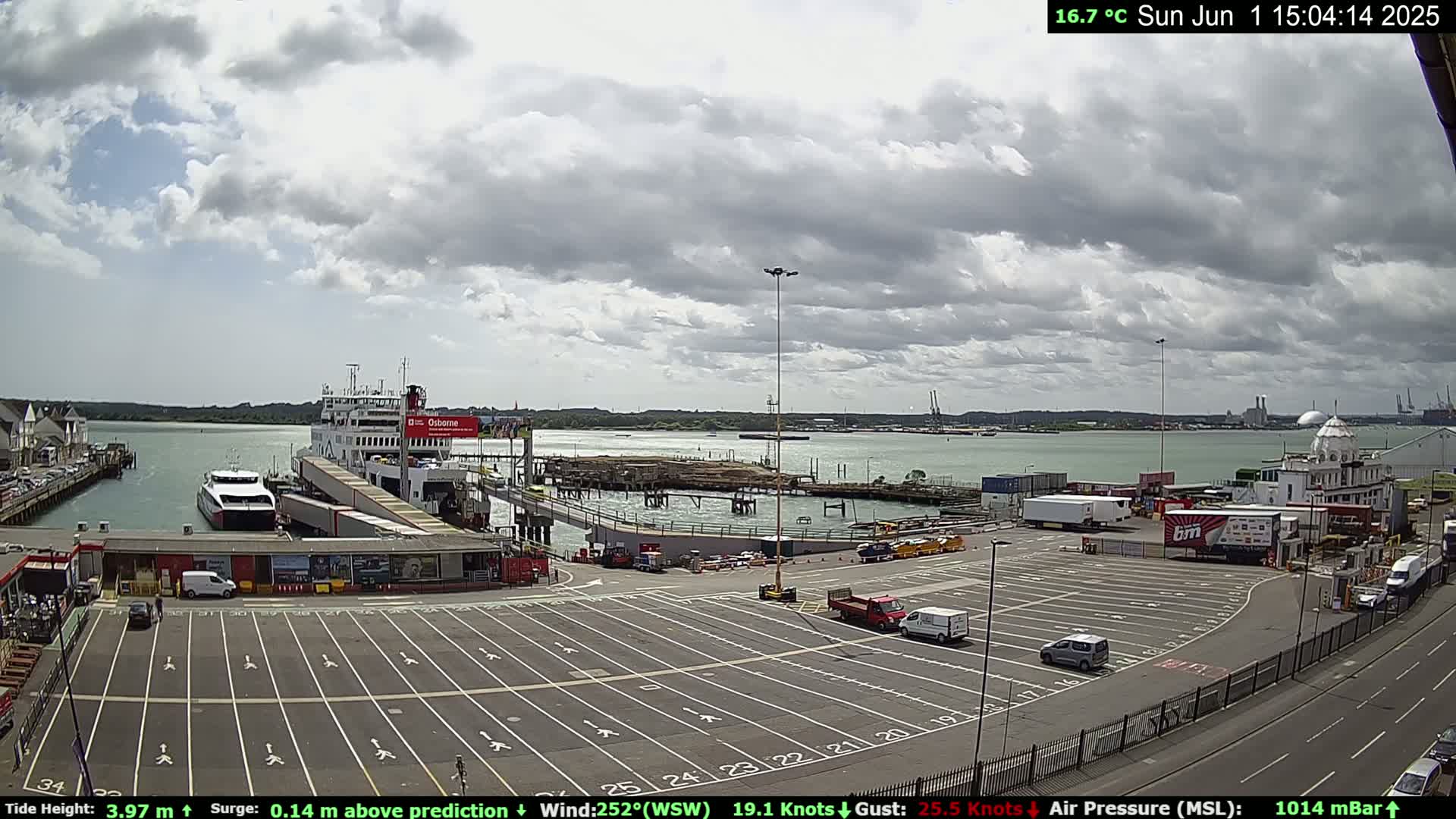 A ferry is docked at a port under a partly cloudy sky.
