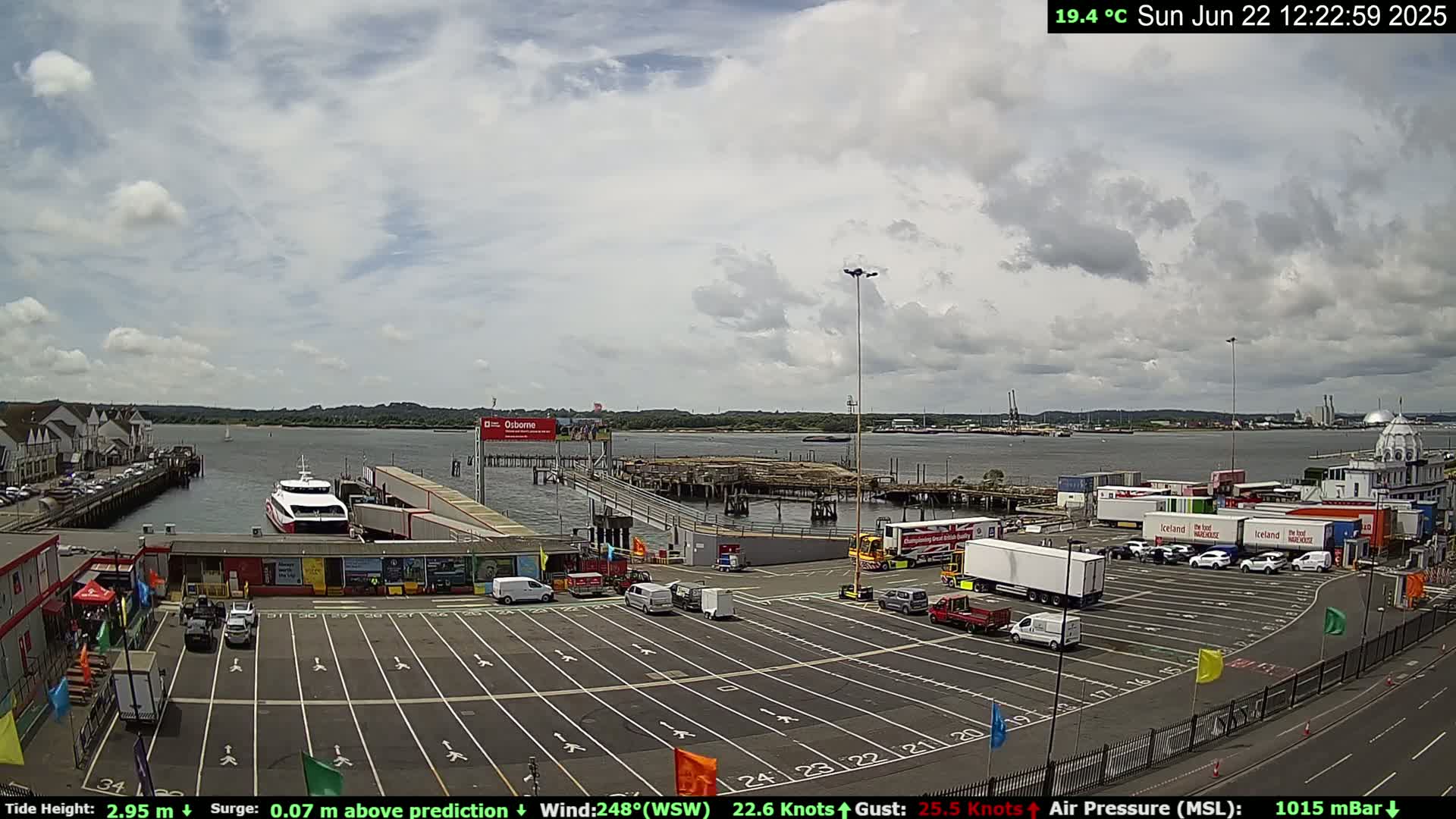 A ferry is docked at a terminal near a body of water under a partly cloudy sky.