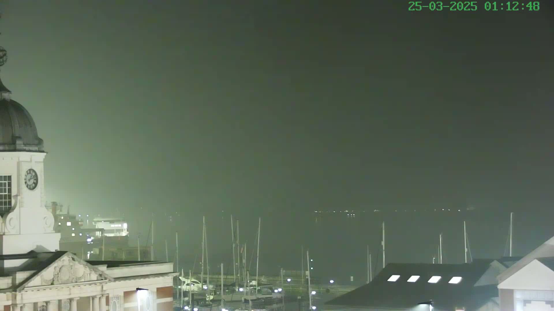 A clock tower and harbor are visible in a hazy, nighttime scene.