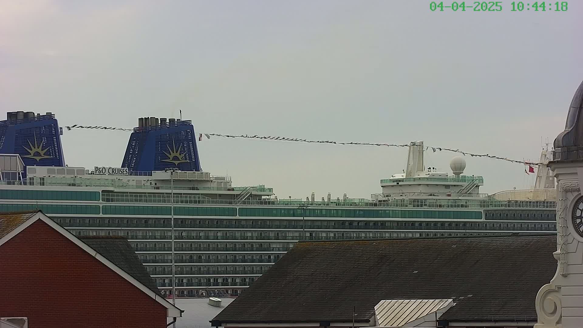 A large cruise ship is partially visible behind some buildings under an overcast sky.