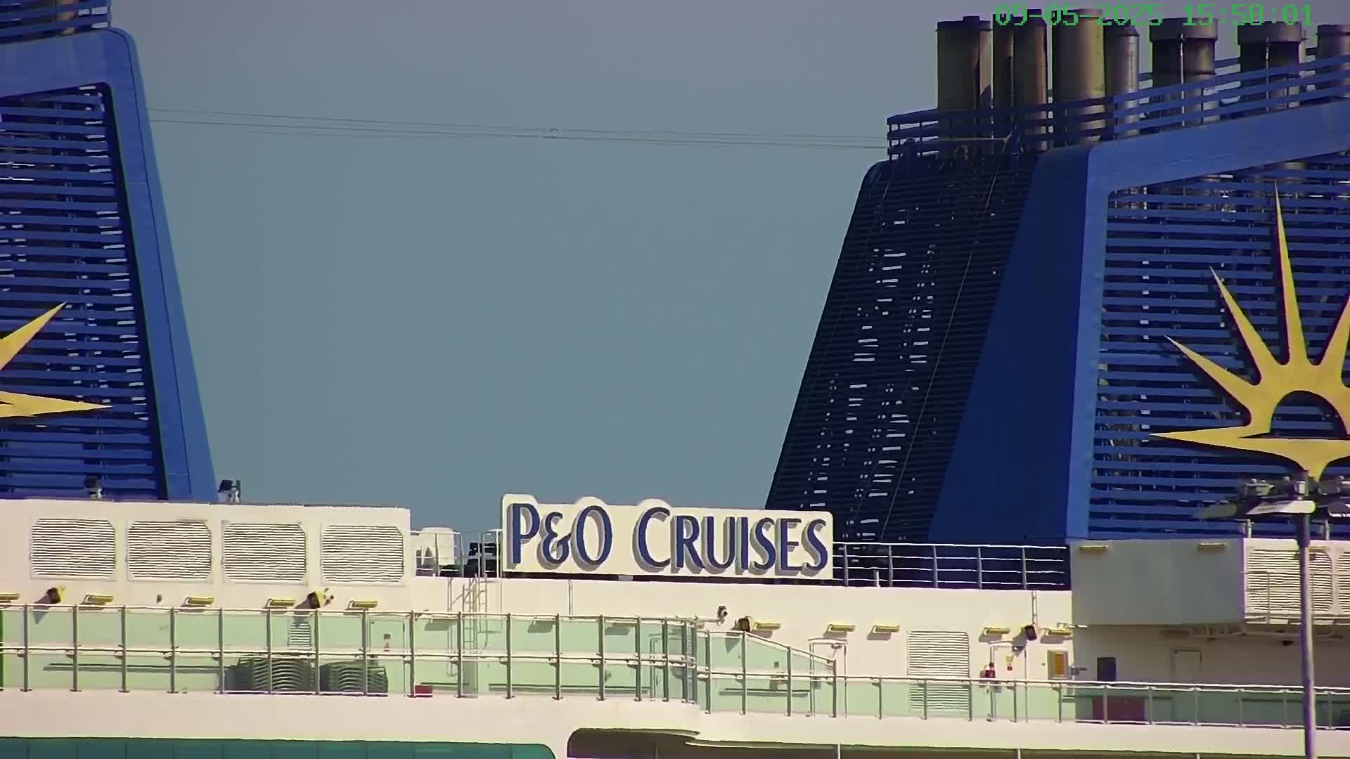 A portion of a P&O Cruises ship is visible on a clear day, showing the ship's upper decks, funnels, and signage.