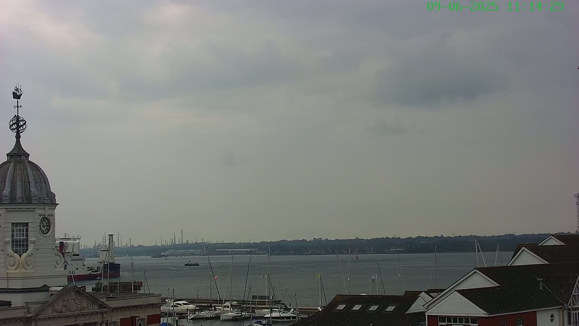 A view of a harbor with numerous boats and buildings under a cloudy sky.