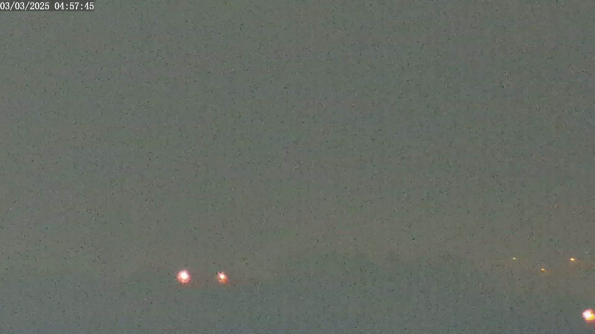 Several faint, distant lights are visible in a muted gray sky.
