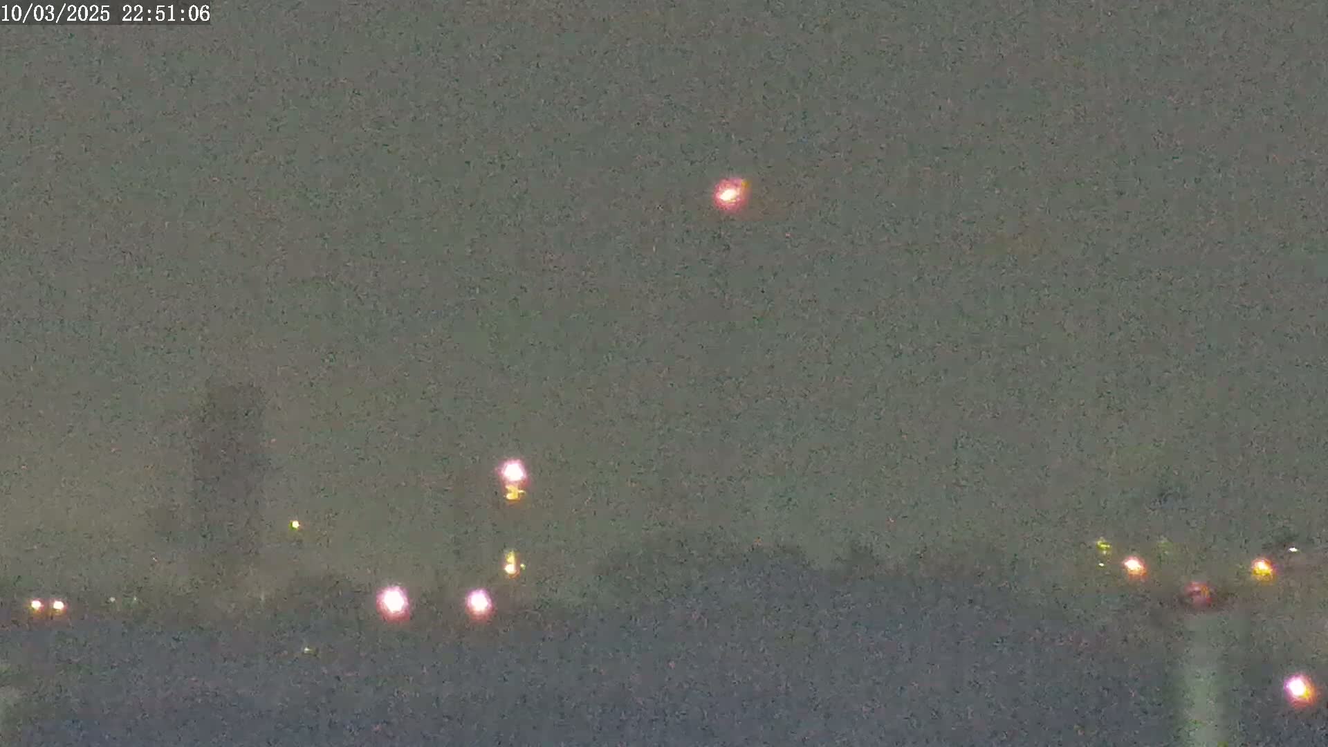 A hazy night scene shows a few distant lights on the horizon and a brighter light higher in the sky.