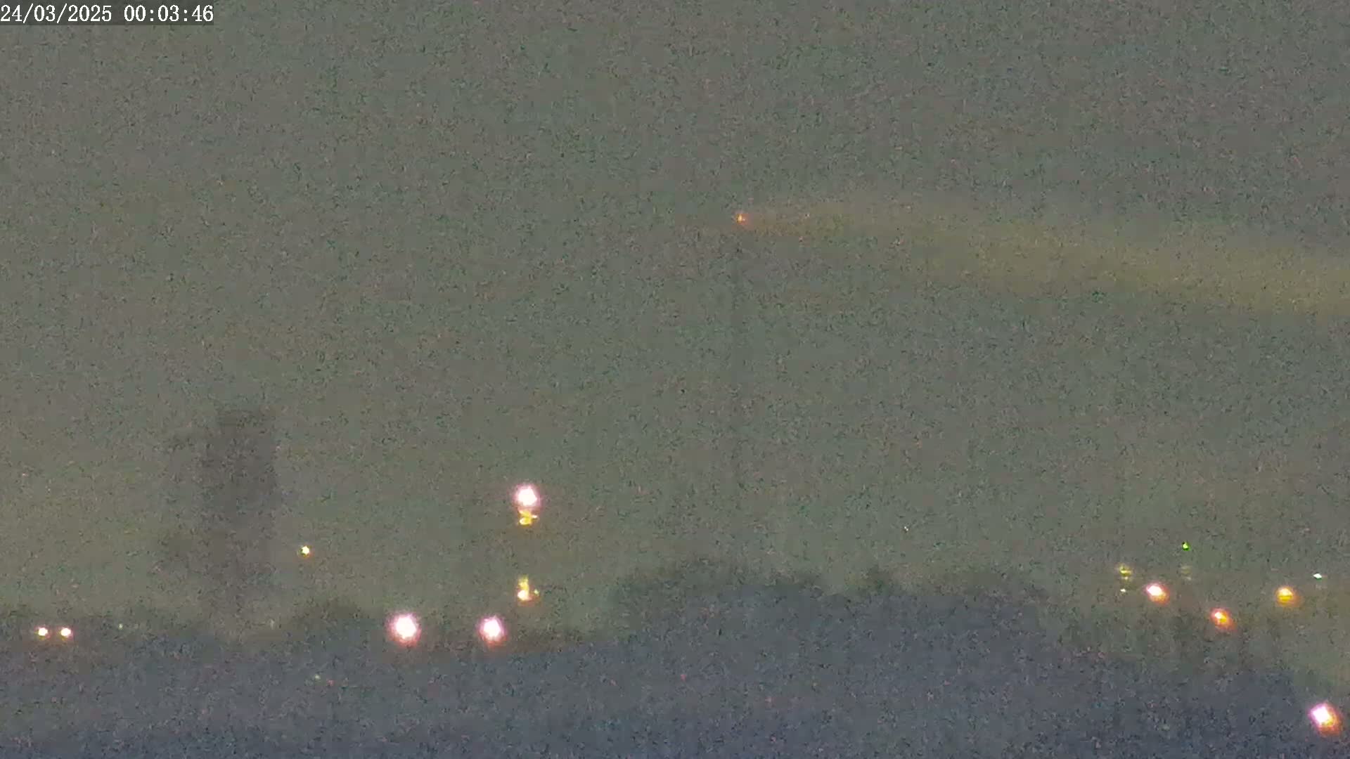 A nighttime long shot shows a blurry, hazy sky with a few distant lights and one bright light possibly in the air.