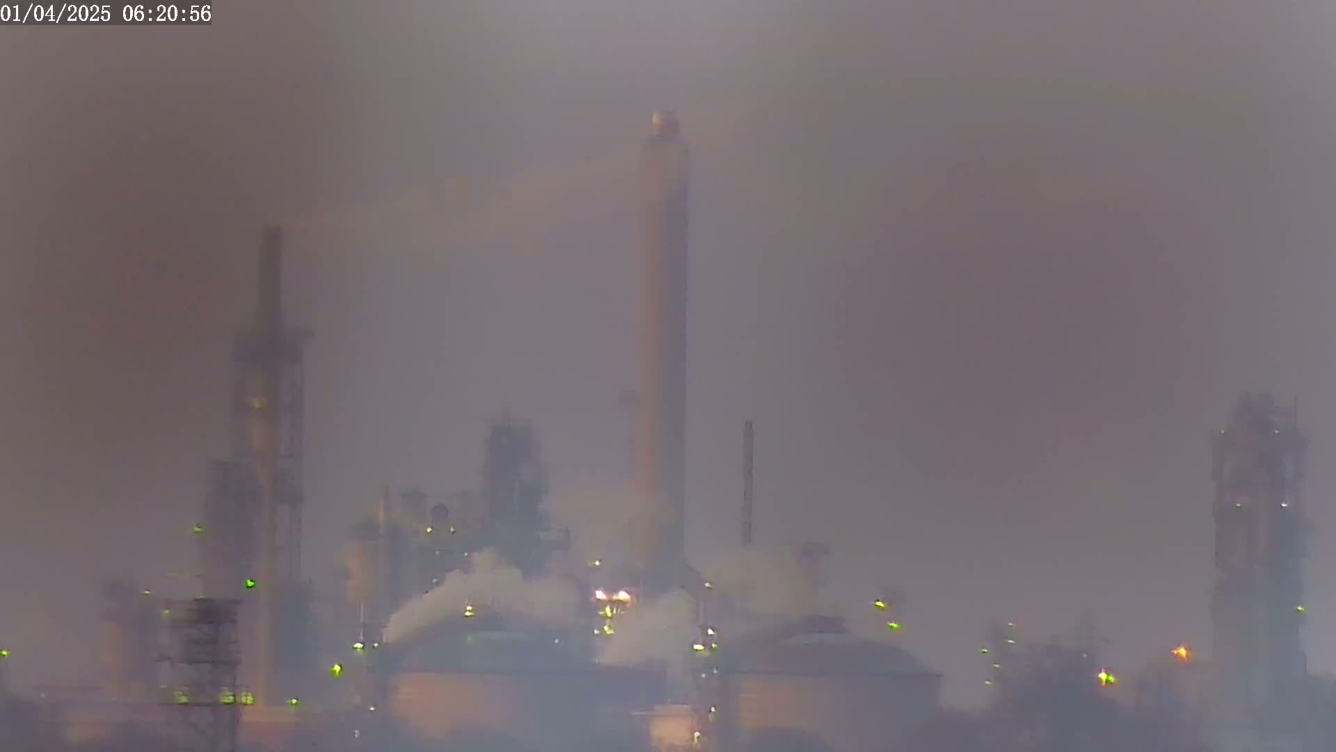 A hazy, foggy industrial complex with tall smokestacks emitting plumes of smoke is visible in the distance.