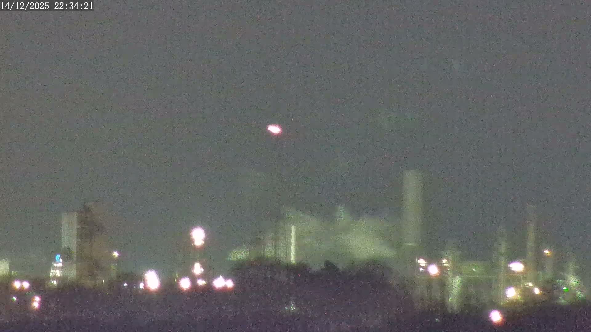 A clear dawn or dusk sky hangs over an industrial scene featuring the top of a blue boat, a flare stack with a bright flame, extensive scaffolding, and numerous factory chimneys emitting plumes of steam.