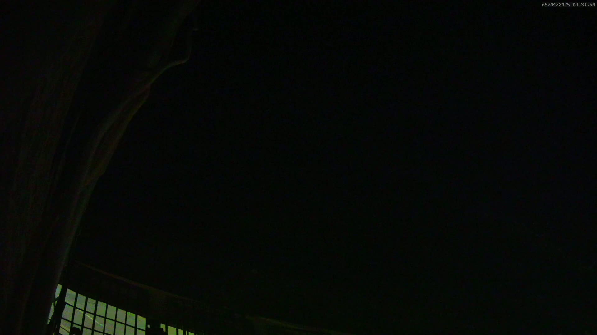 A nighttime, low-angle view shows a dark sky above a curved, windowed structure.
