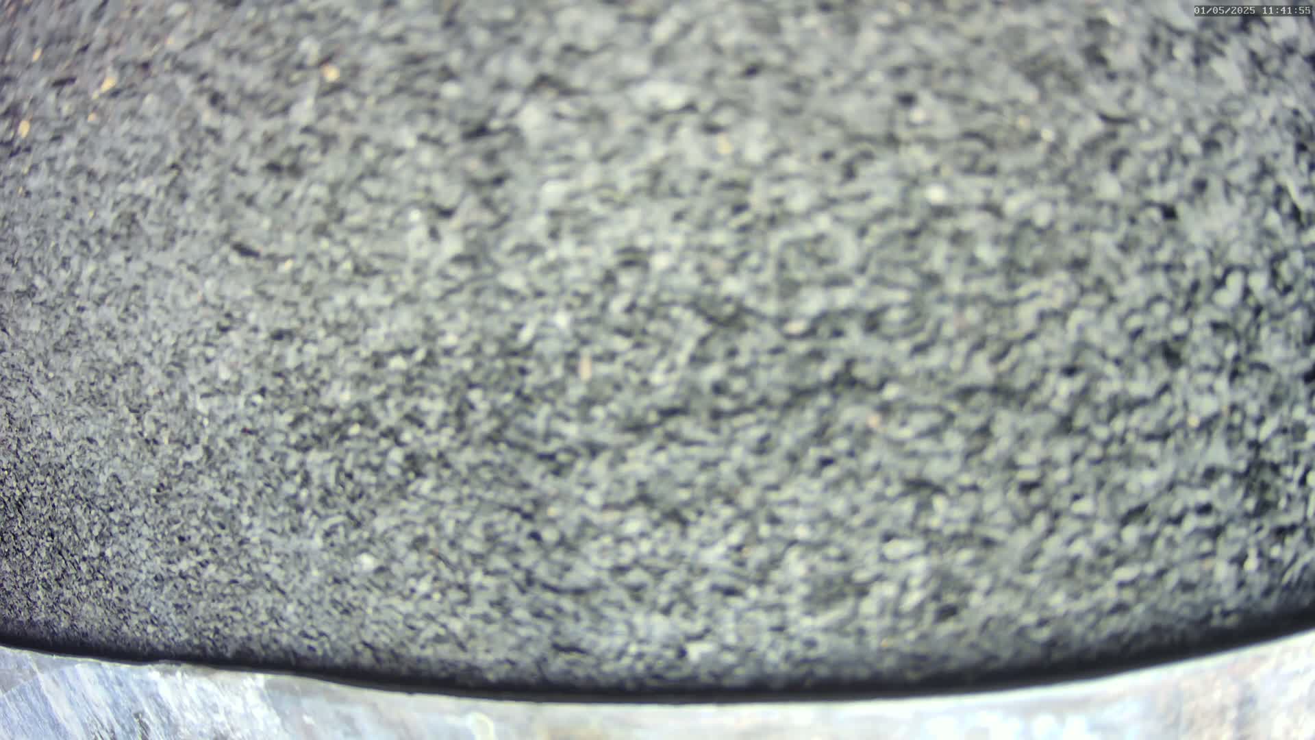A blurry close-up shows a dark gray, granular surface.