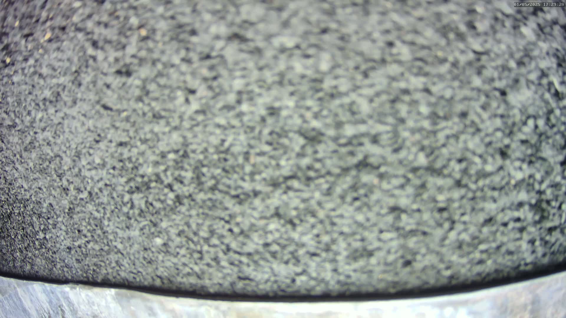 A close-up view shows a textured, dark gray surface, possibly asphalt or a similar material.