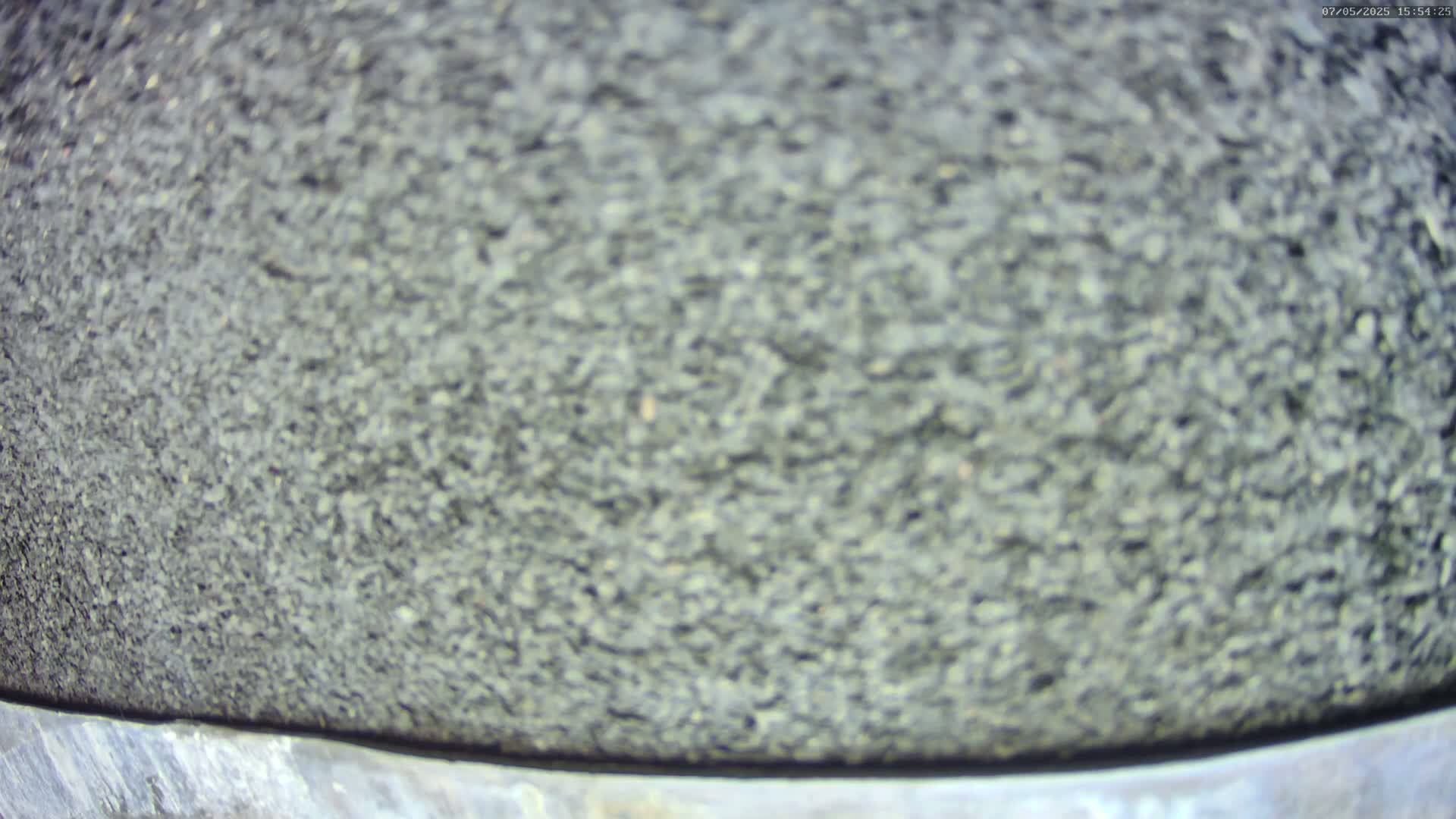A blurry close-up shows a dark gray, textured surface, possibly asphalt or a similar material.
