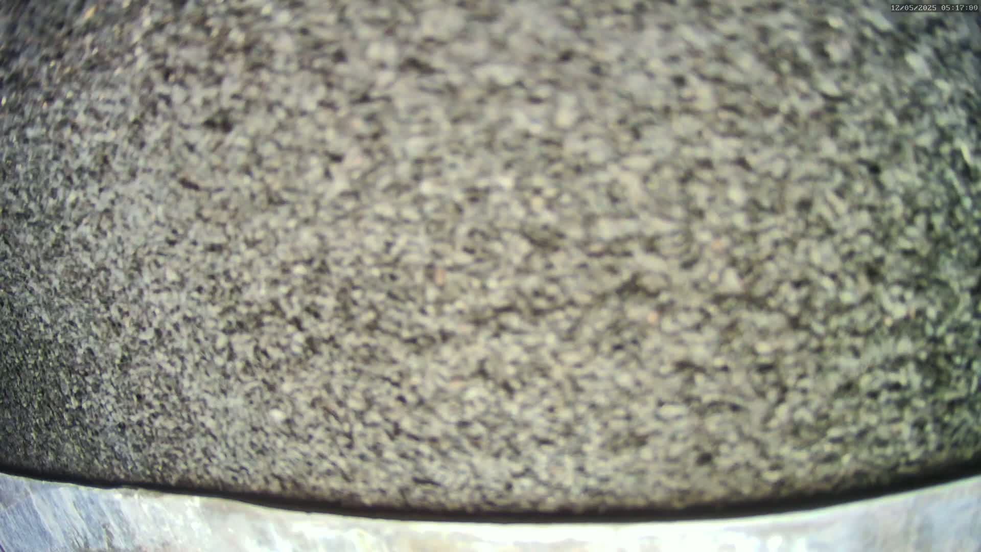 A blurry close-up shows a dark gray, textured surface, possibly asphalt, ending at a metallic gray edge.