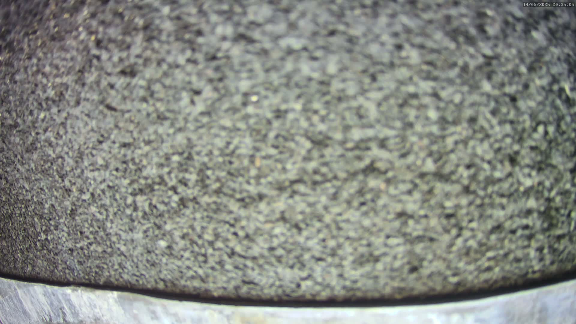 A close-up view shows a dark gray, coarse-textured surface atop a lighter gray band.