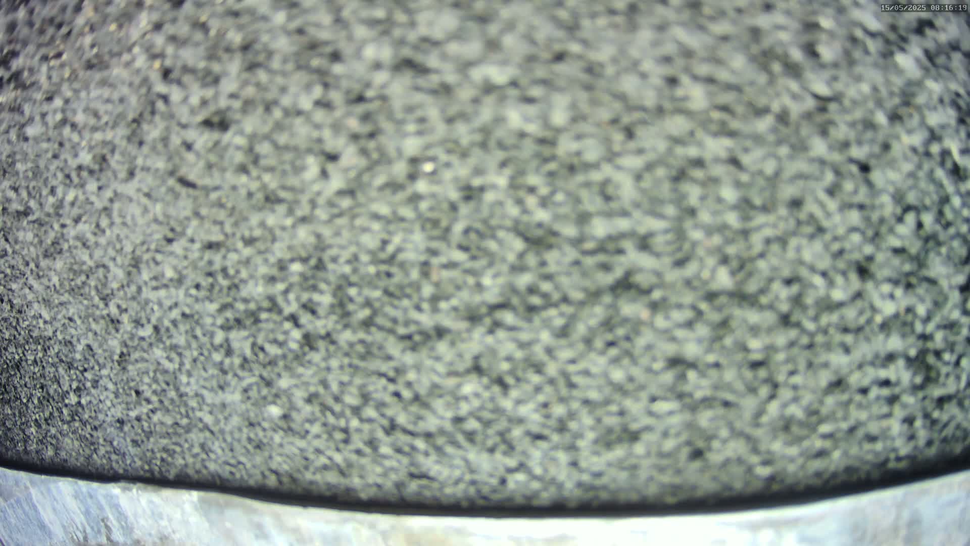 A blurry close-up shows a dark gray, granular surface, possibly asphalt, with a metallic edge at the bottom.