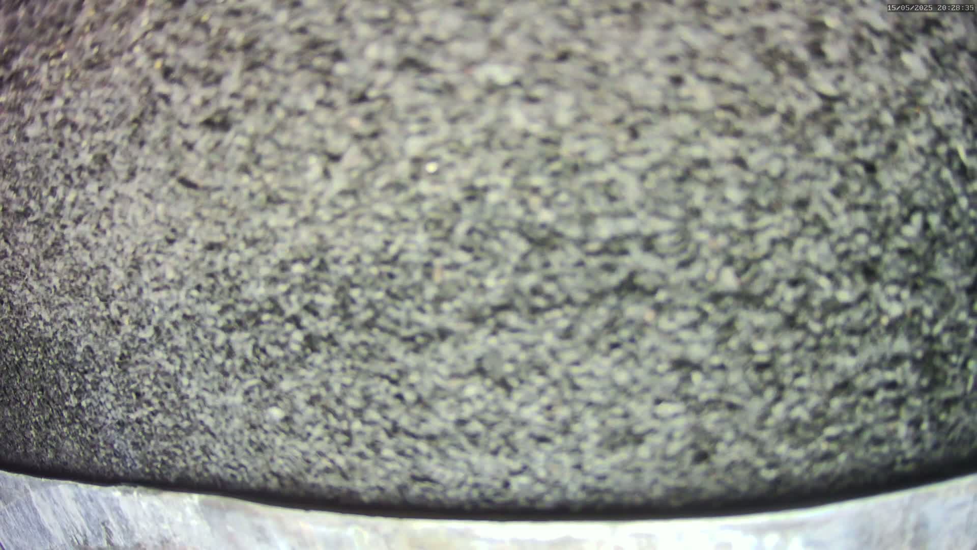 A blurry close-up shows a dark gray, granular surface atop a metallic band.