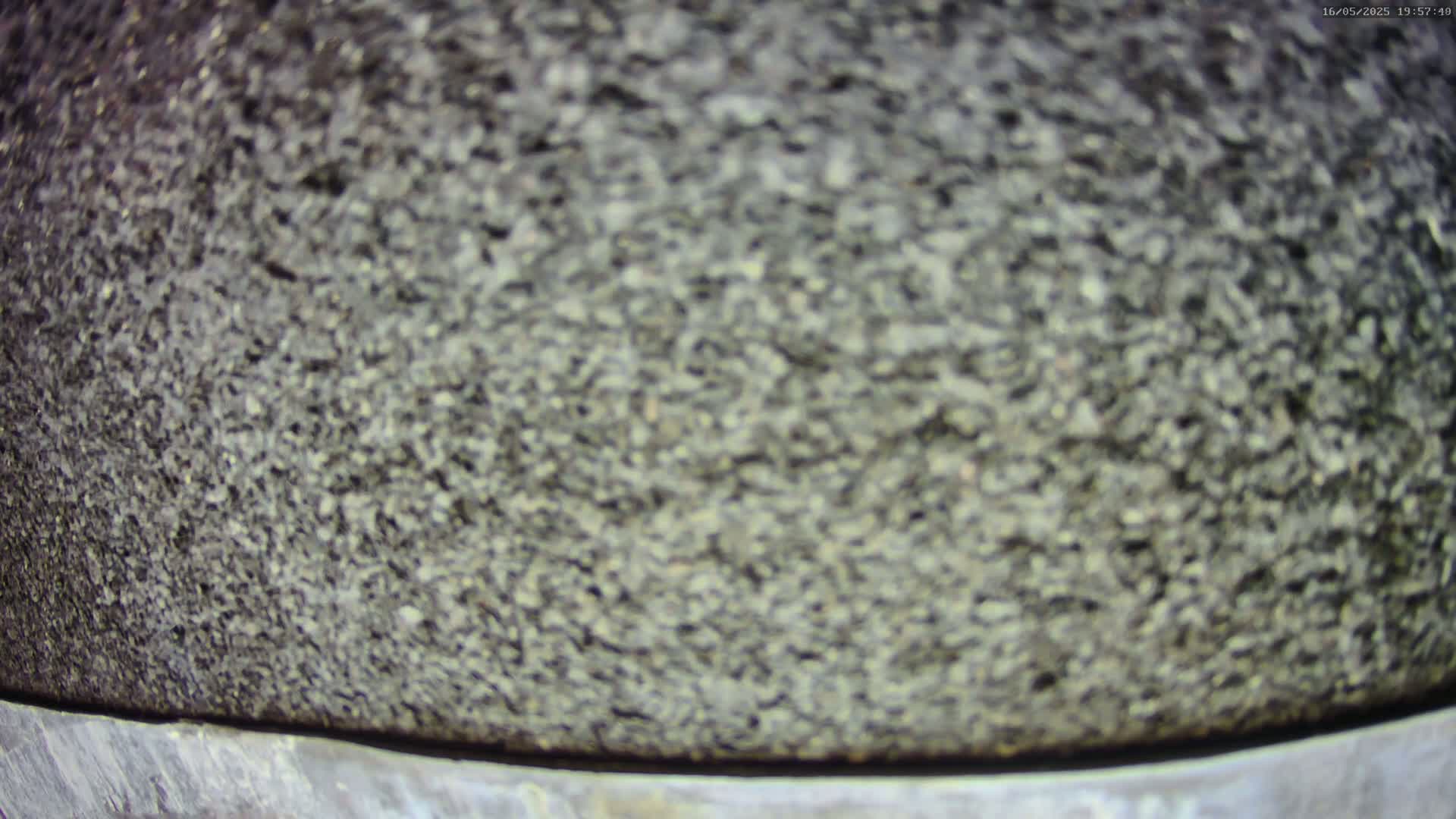 A close-up view shows a coarse, dark gray textured surface, possibly stone or asphalt.