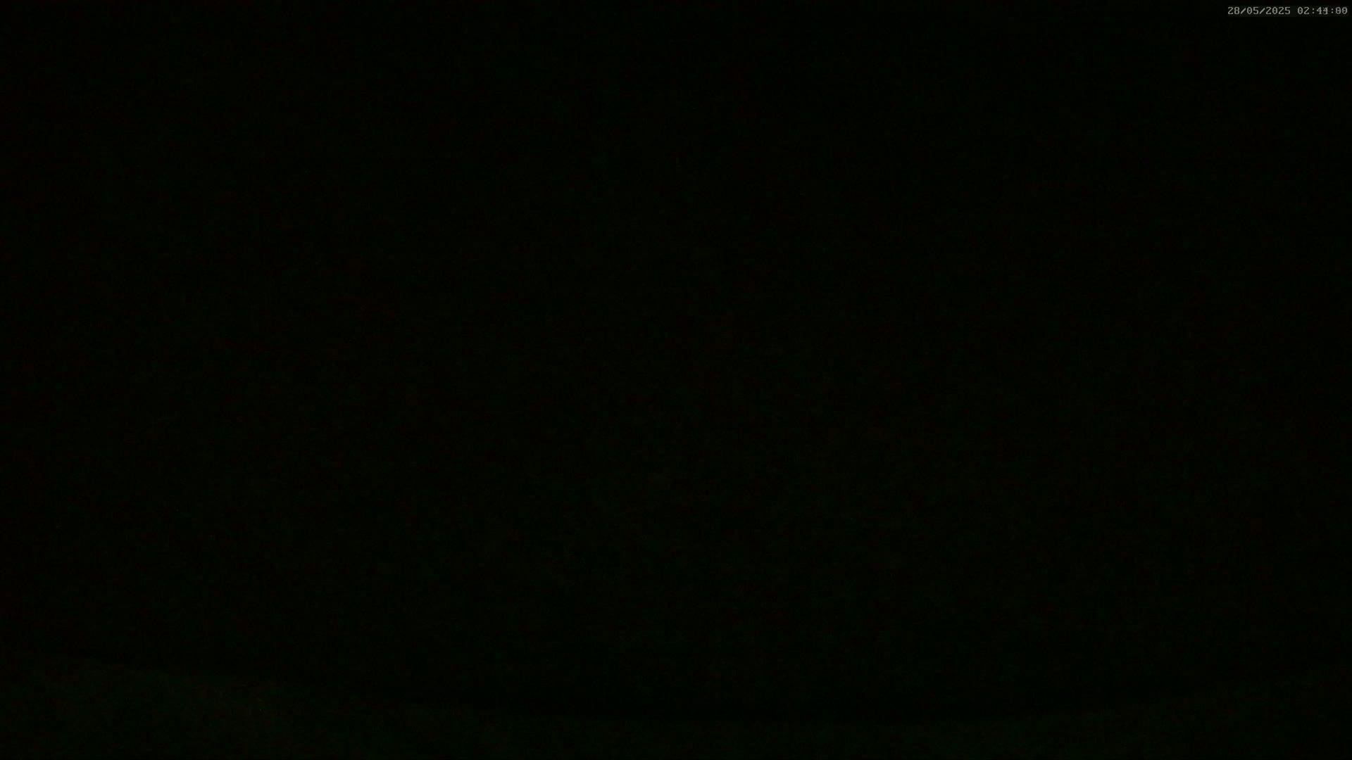 The image is almost entirely black, with a very faint suggestion of a dark, indistinct landscape at the very bottom.