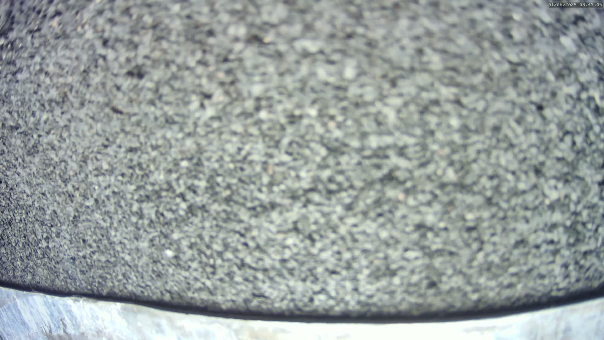A close-up view shows a textured surface of dark gray small stones.
