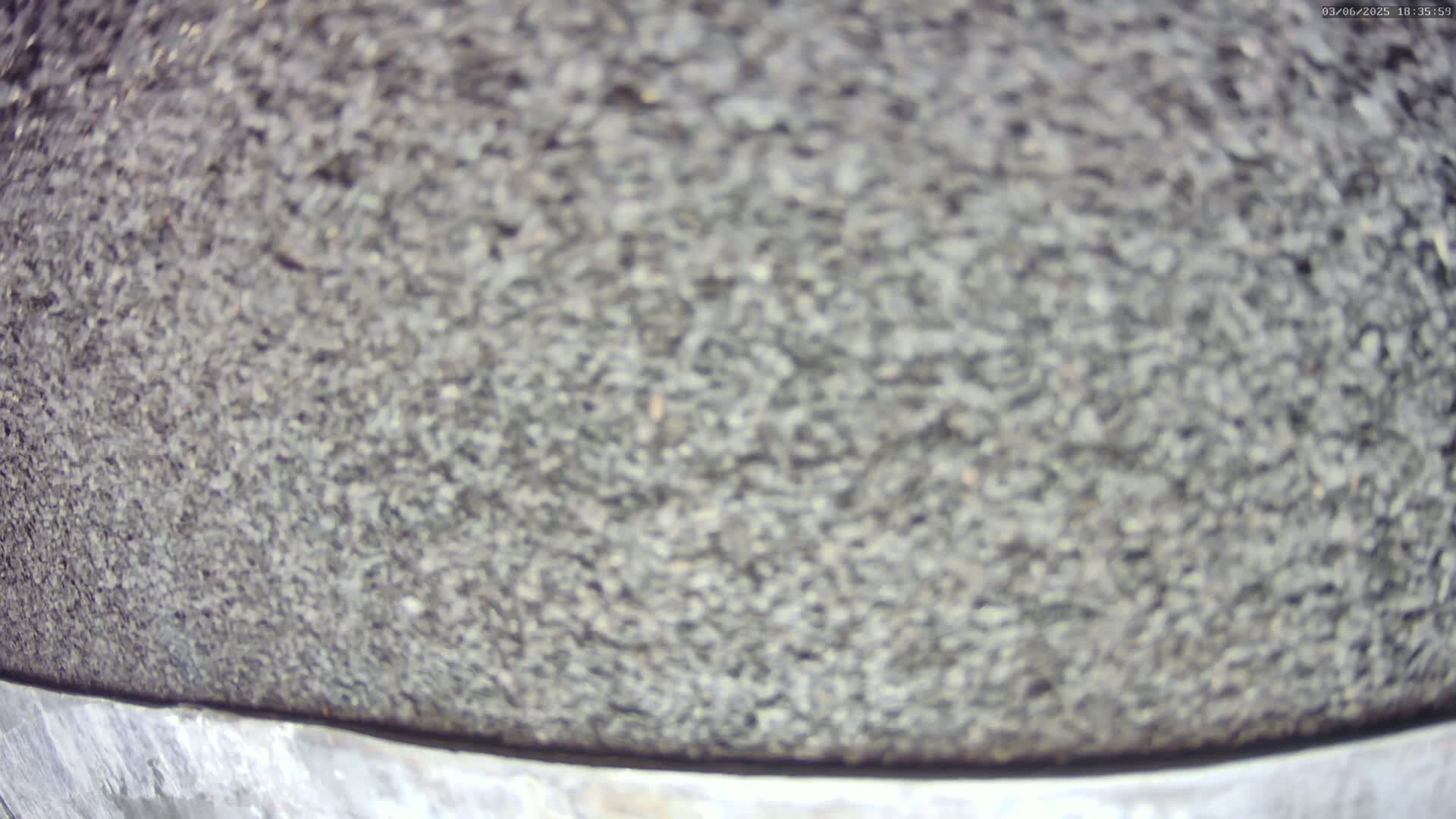 A close-up view shows a textured, dark gray surface, possibly asphalt or a similar material.