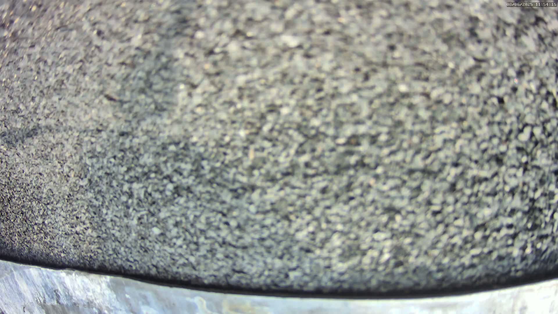 A close-up view shows a textured surface of dark gray gravel.