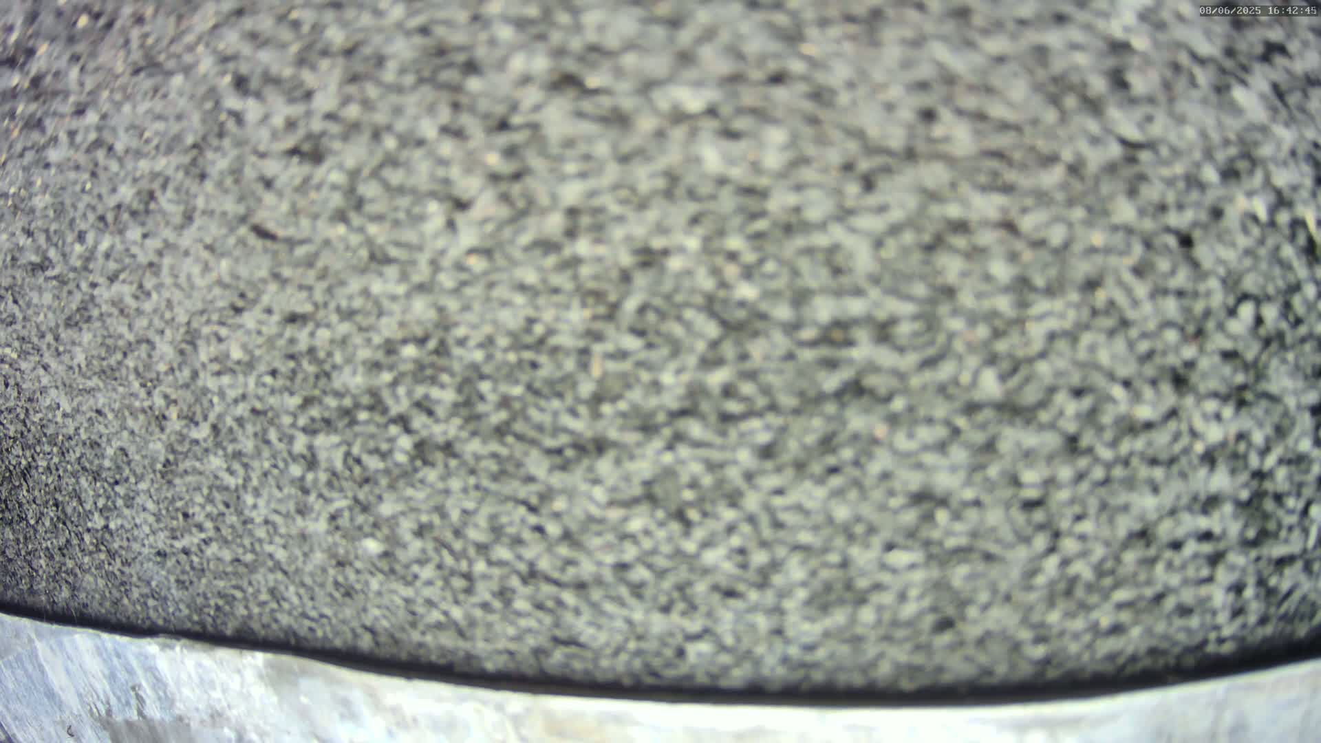 A close-up view shows a blurred expanse of dark gray, small, pebble-like material.