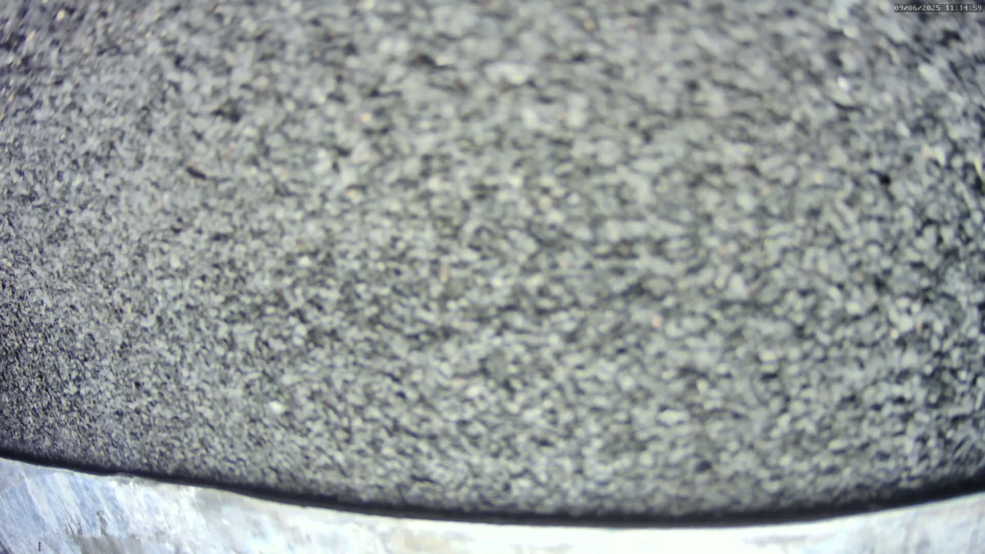 A blurry close-up shows a dark gray, coarse-textured surface, possibly asphalt or gravel.
