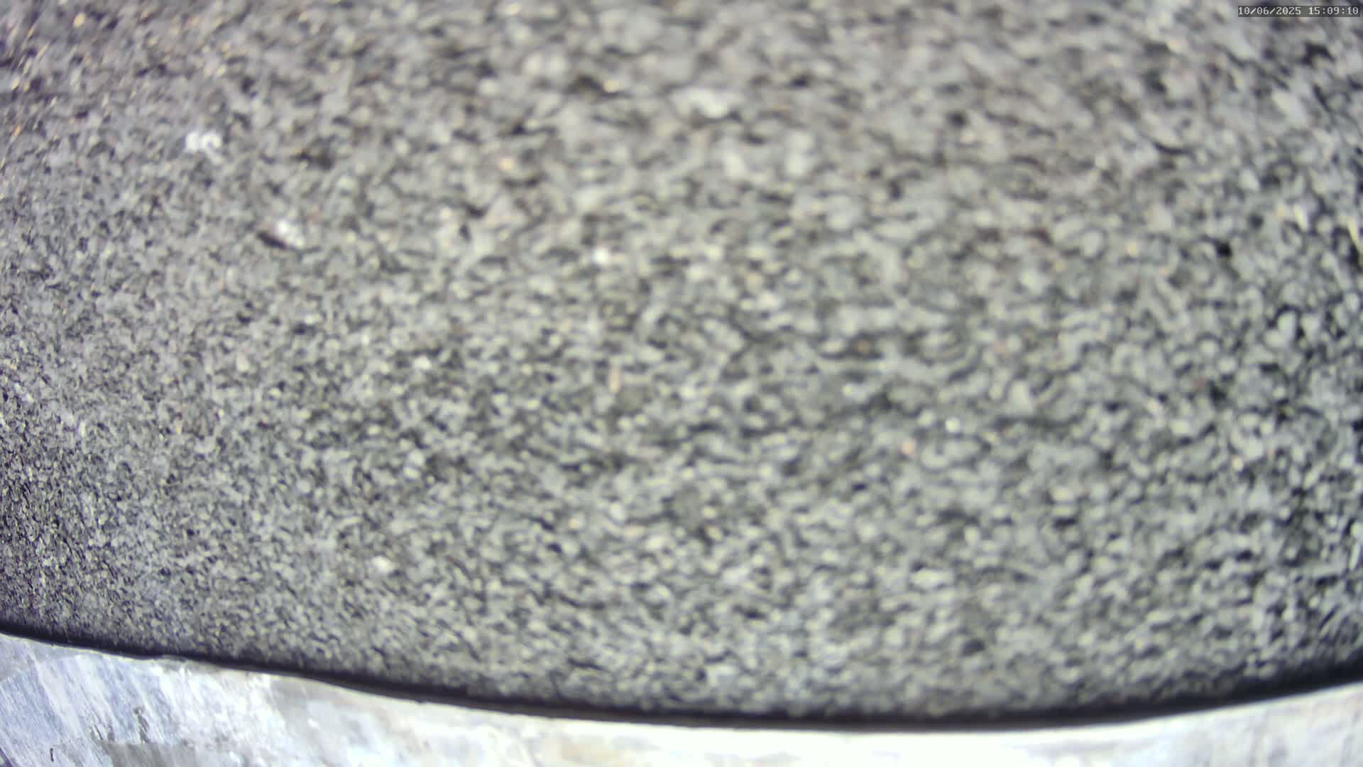 A close-up view shows a textured surface of dark gray, small, loose stones.