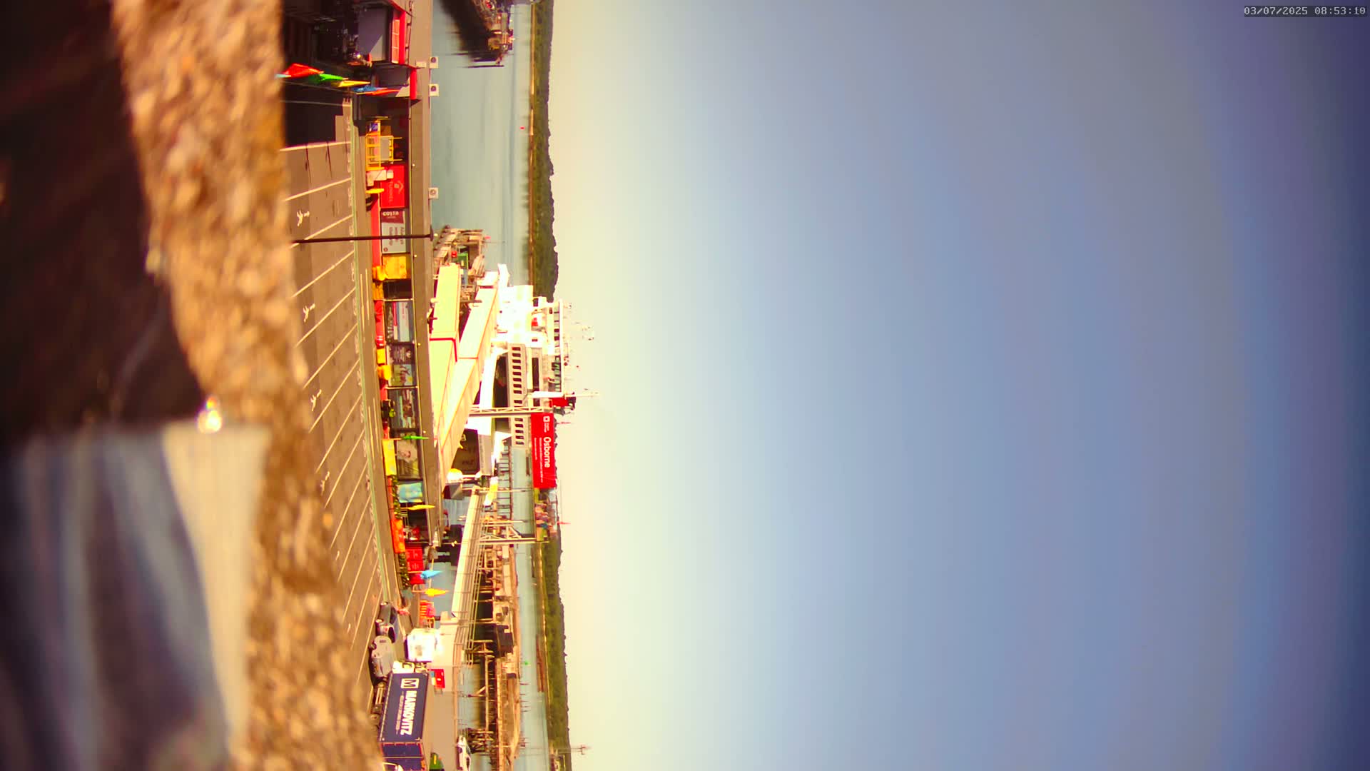 A ferry is docked at a port on a calm, sunny day.