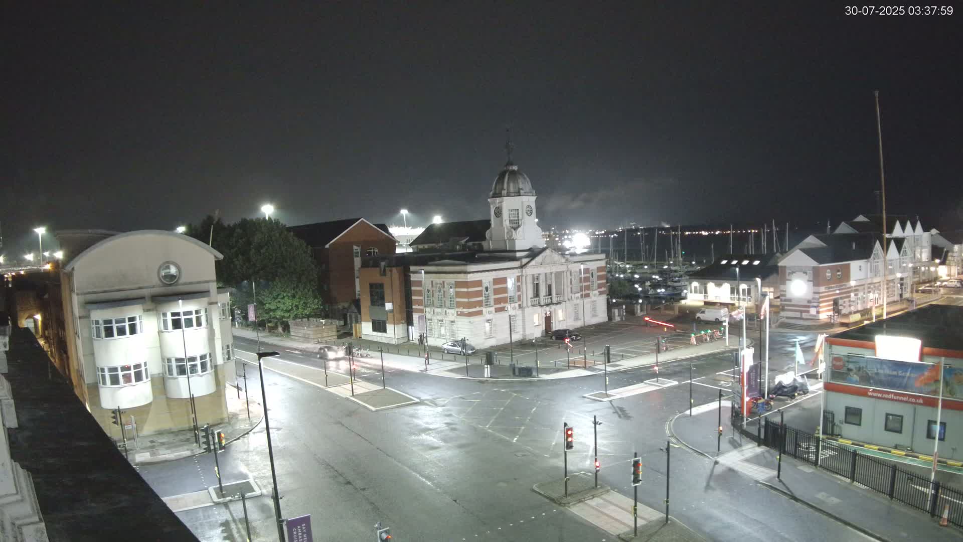 An overcast day reveals a city street scene with several buildings, including a large brick building with a dome, and a marina visible in the distance.