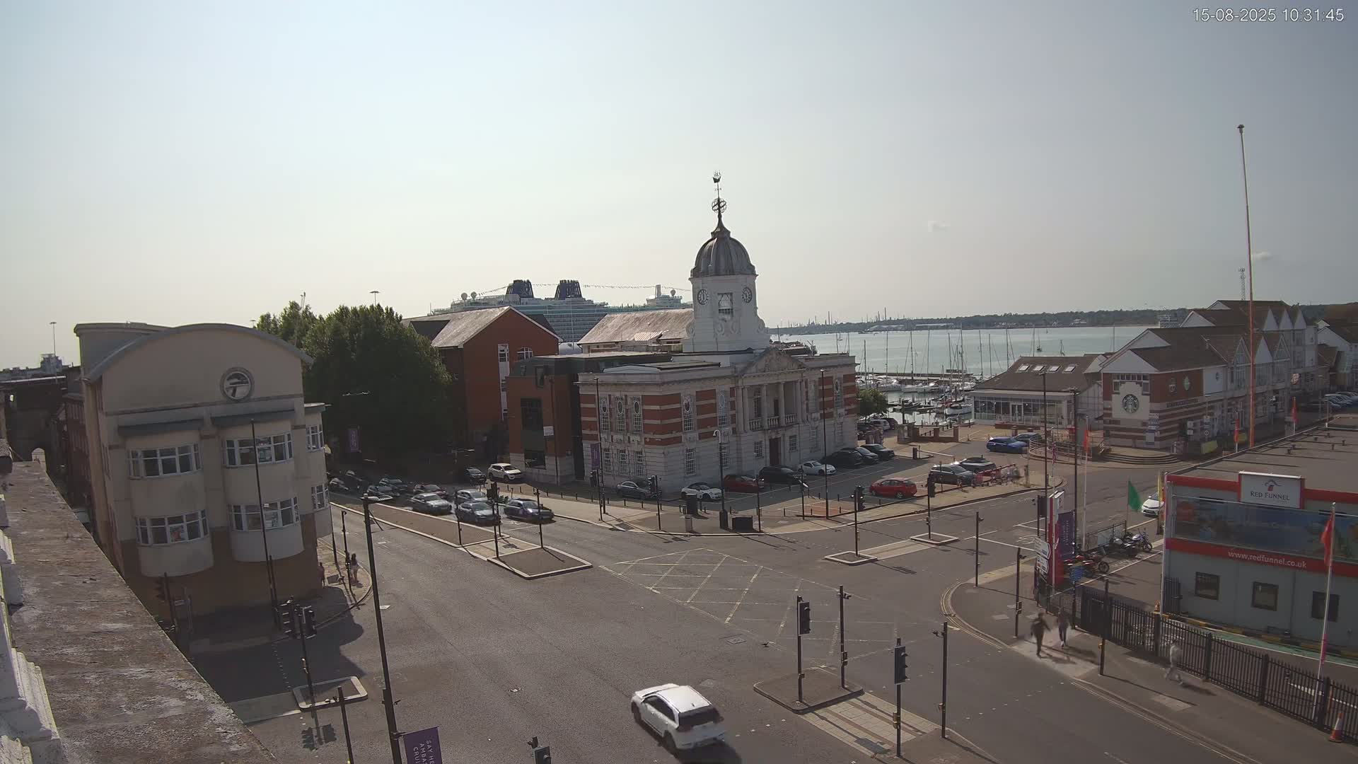 An overcast day reveals a city street scene with several buildings, including a large brick building with a dome, and a marina visible in the distance.